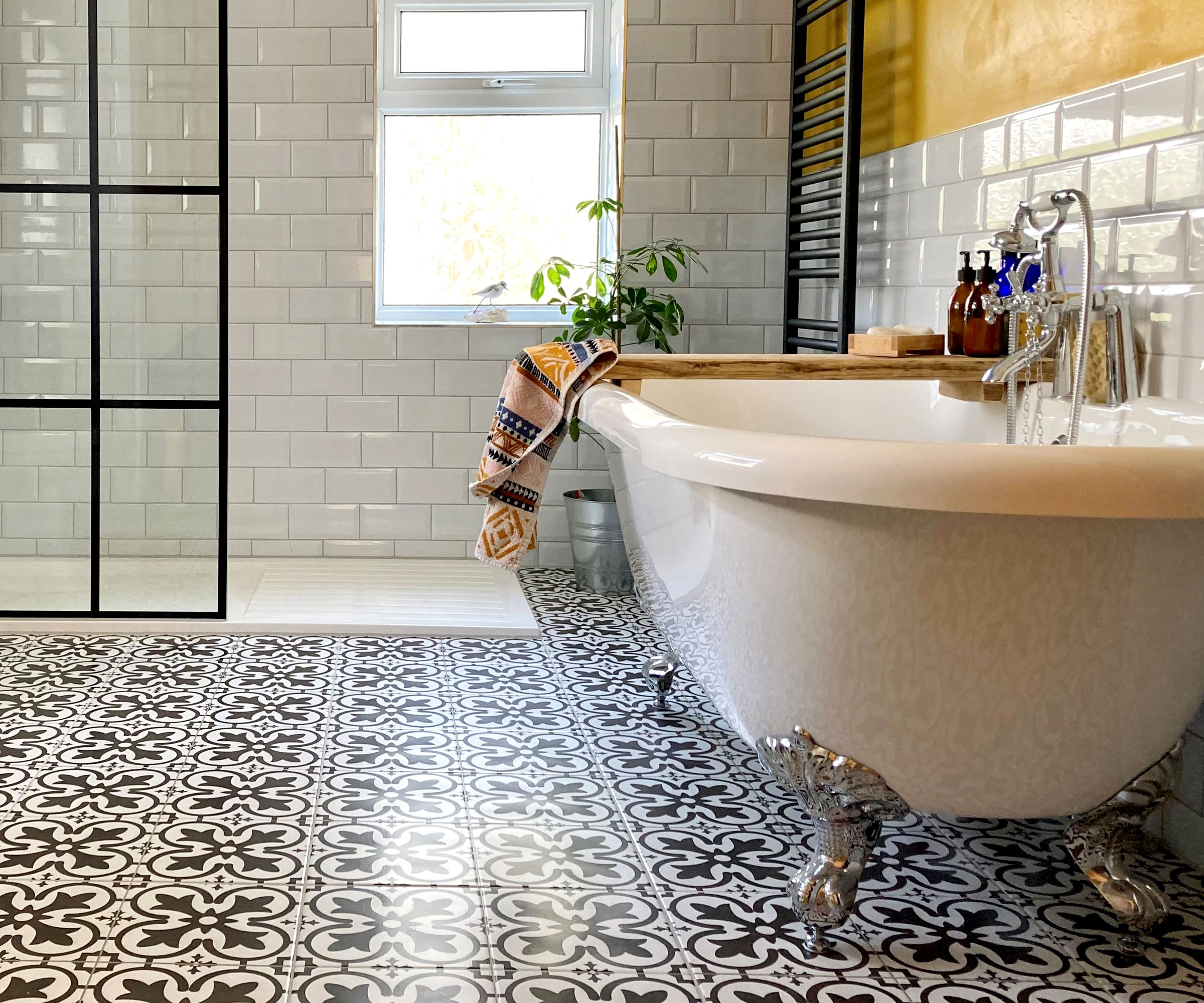 Large bathroom with white metro wall tiles, roll top bath with chrome feet and Victorian style floor tiles