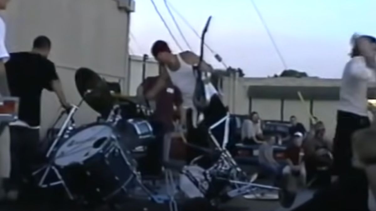 A destroyed drum kit on a stage in a car park