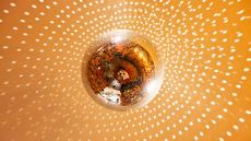 A gold-tinted disco ball reflecting light onto a gold ceiling