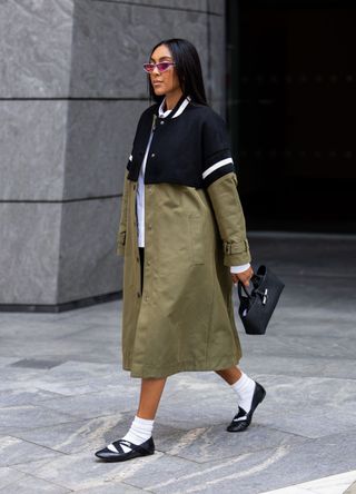 Tayshia Adams wears Longchamp green and black coat with socks and ballet flats