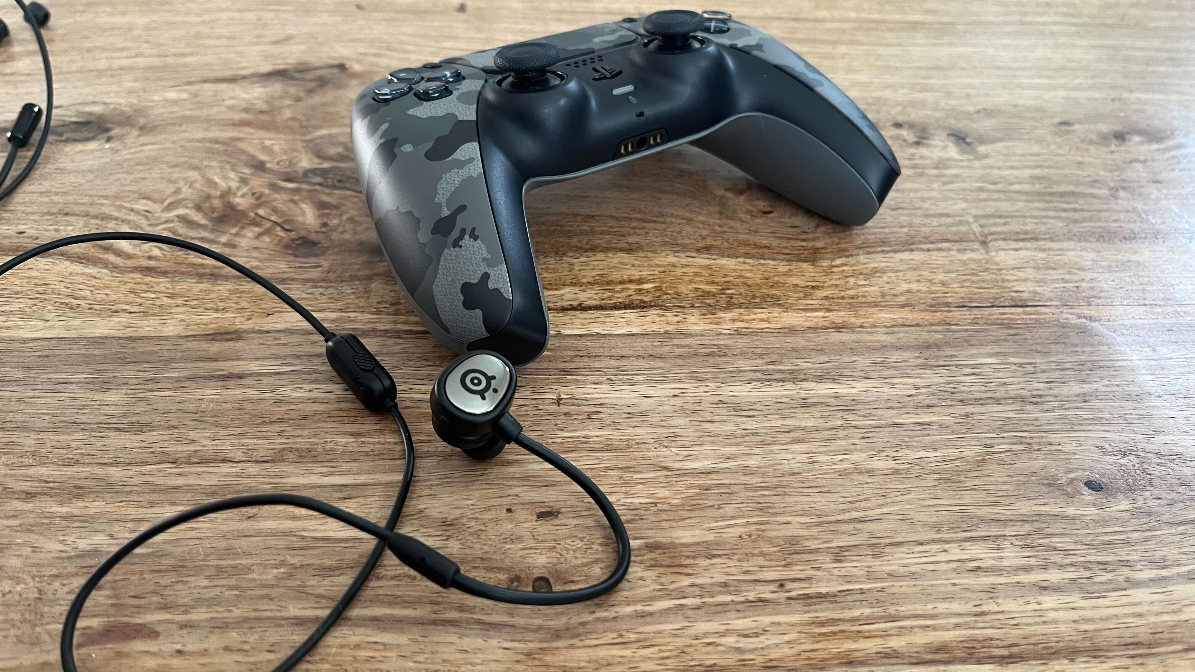 SteelSeries Tusq gaming earbuds and a PS5 controller.
