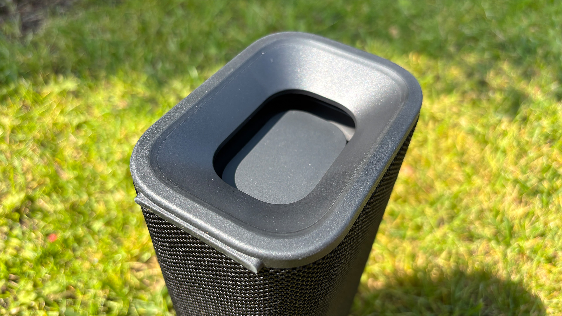 Sony ULT Field 3 wireless speaker stood on end on grassy lawn, close up on end of speaker