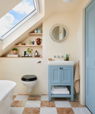 soft pink painted loft bathroom with checkerboard tile floor and a small blue vanity