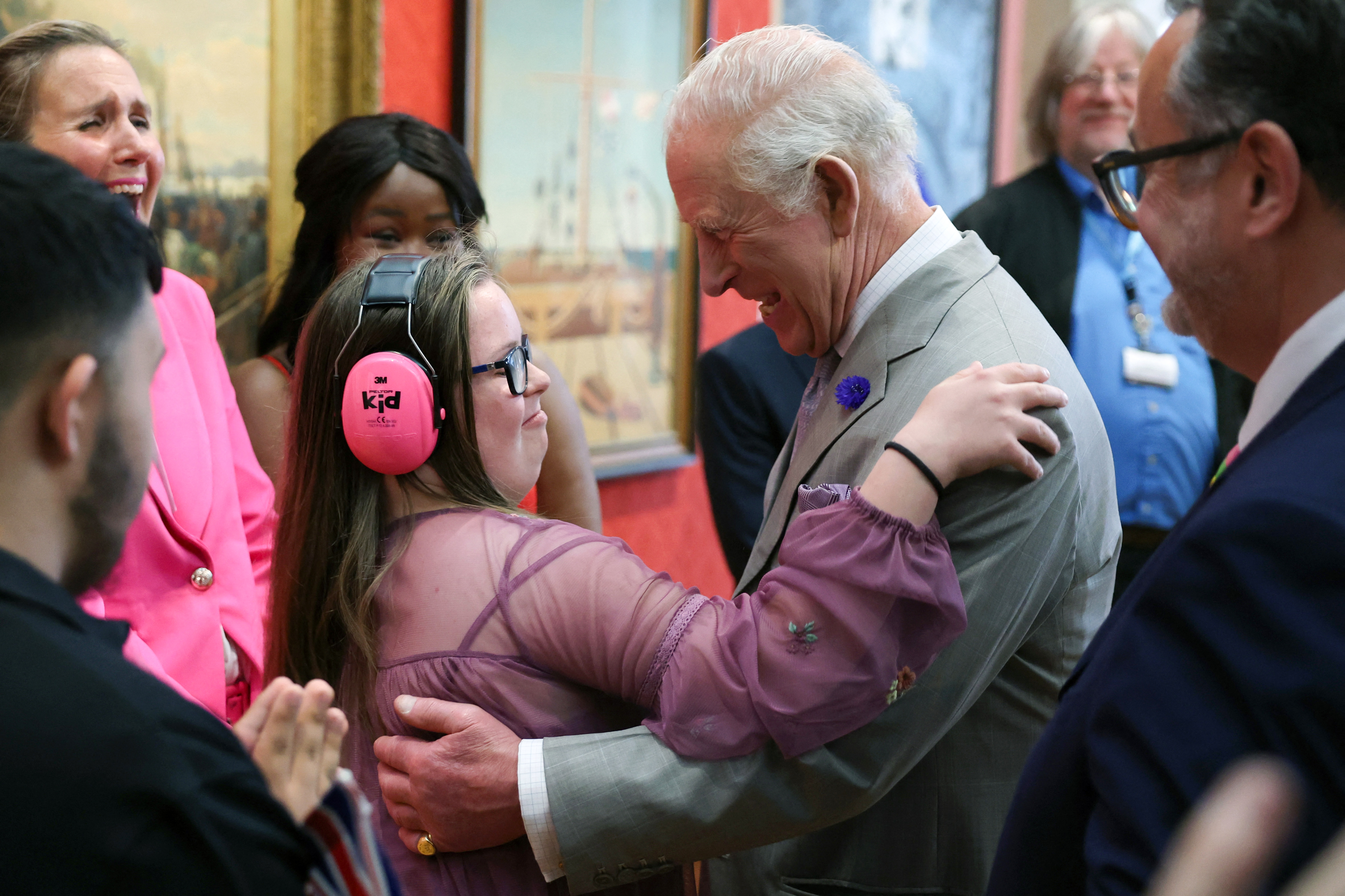 King Charles hugging a teenage girl wearing pink headphones