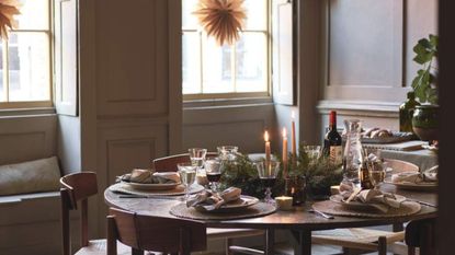 brown living room with a round wooden table set for Christmas dinner