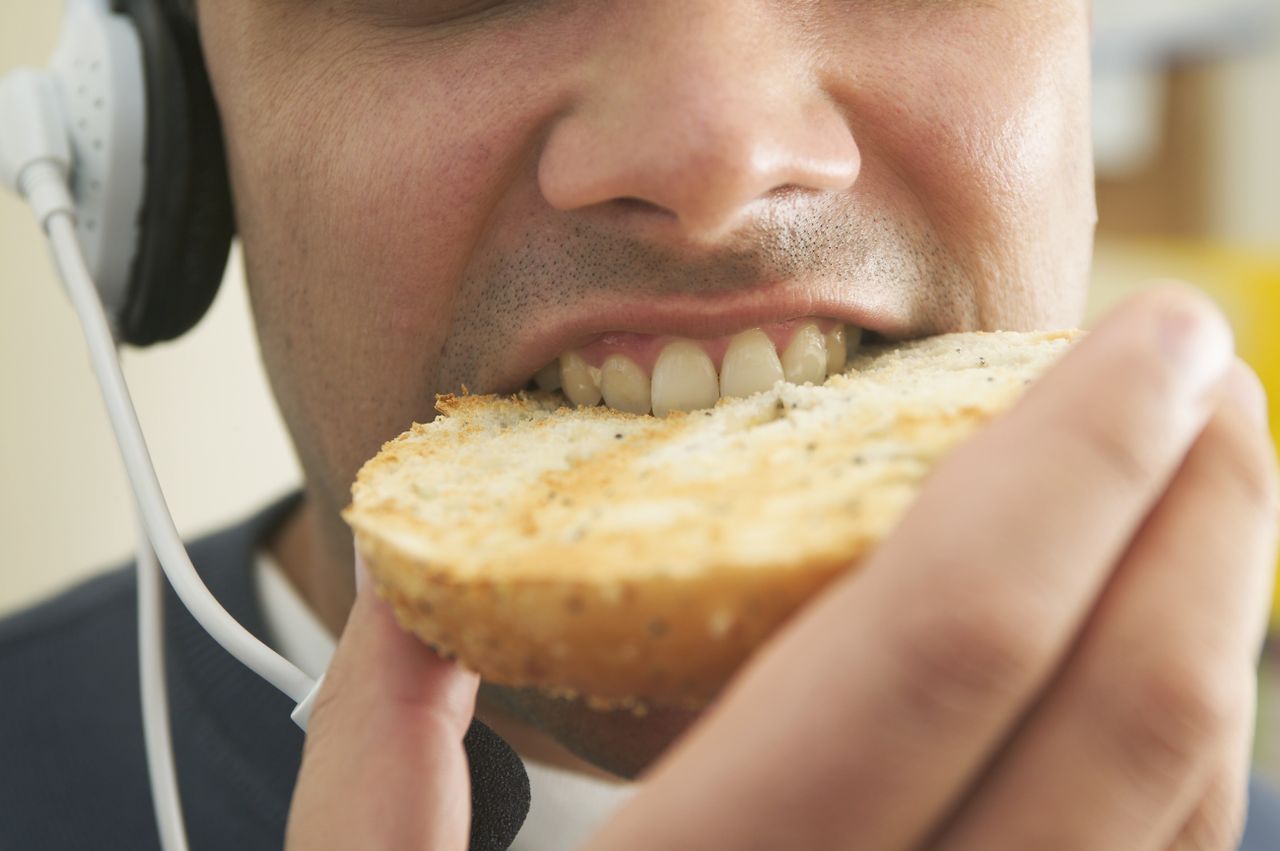 A man eating a bagel and listening to podcasts