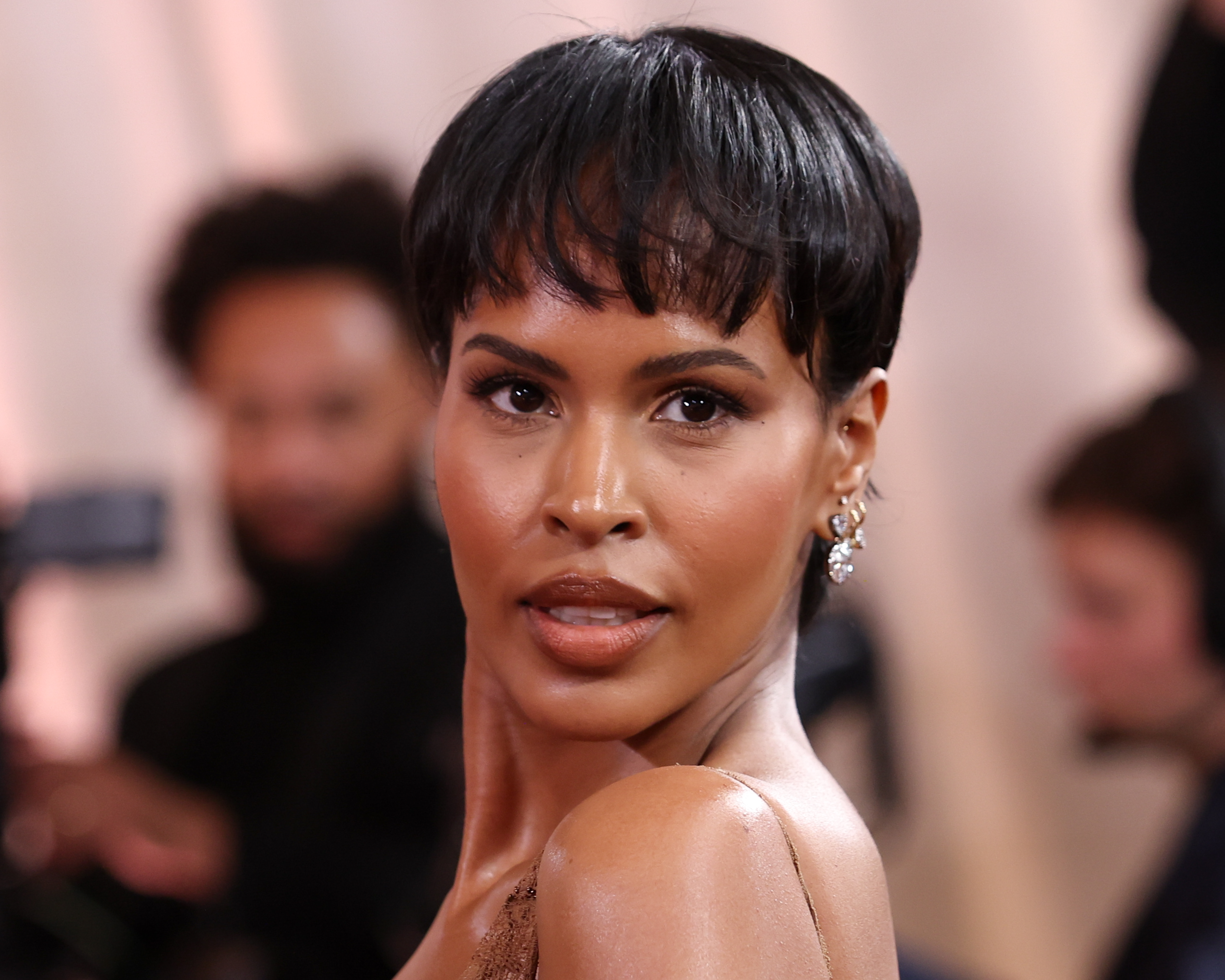 a black woman with short, dark hair poses on a red carpet