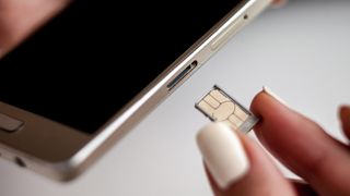 A person inserting a SIM card into a smartphone.