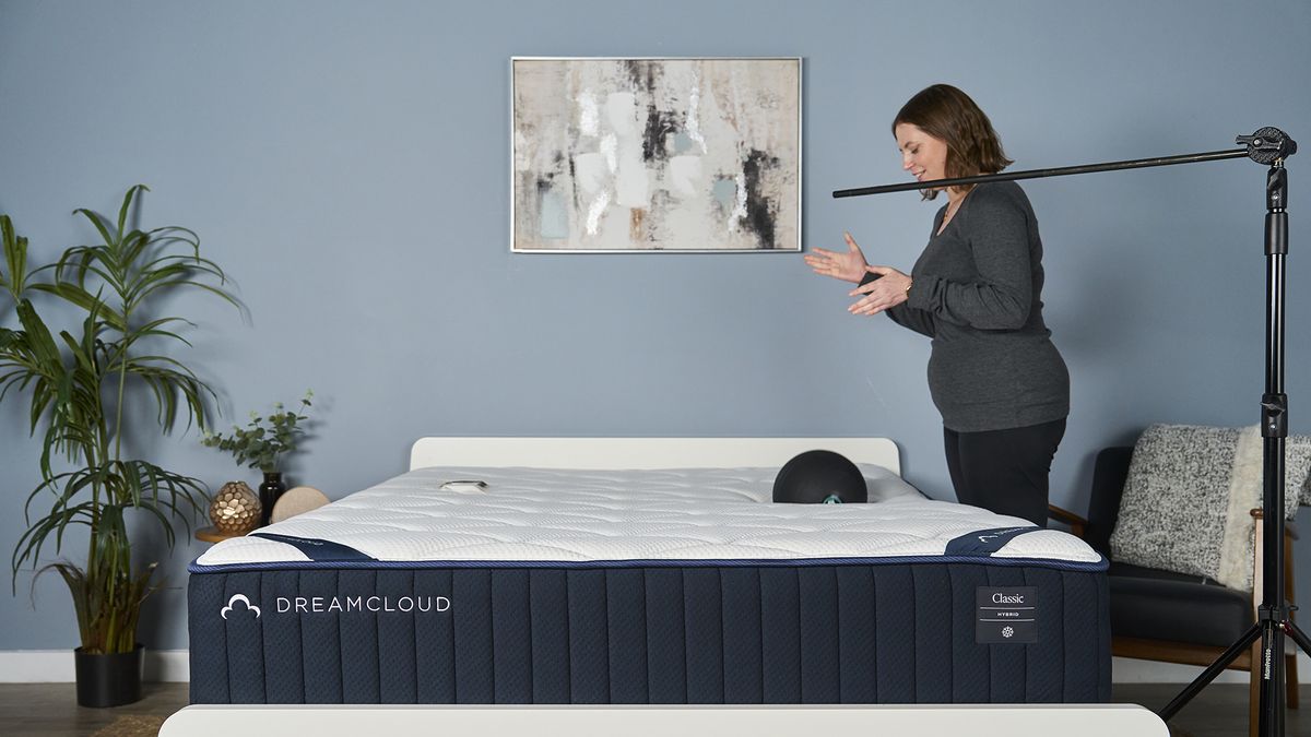 A Tom's Guide tester holds a 5kg slam ball over the DreamCloud Classic and then drops it, while an accelerometer on the other side of the mattress measures how much motion is absorbed
