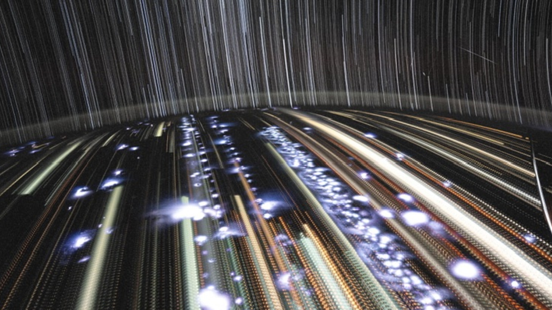 A view of Earth from space with streaks of light from storms and cities, with star streaks overhead.