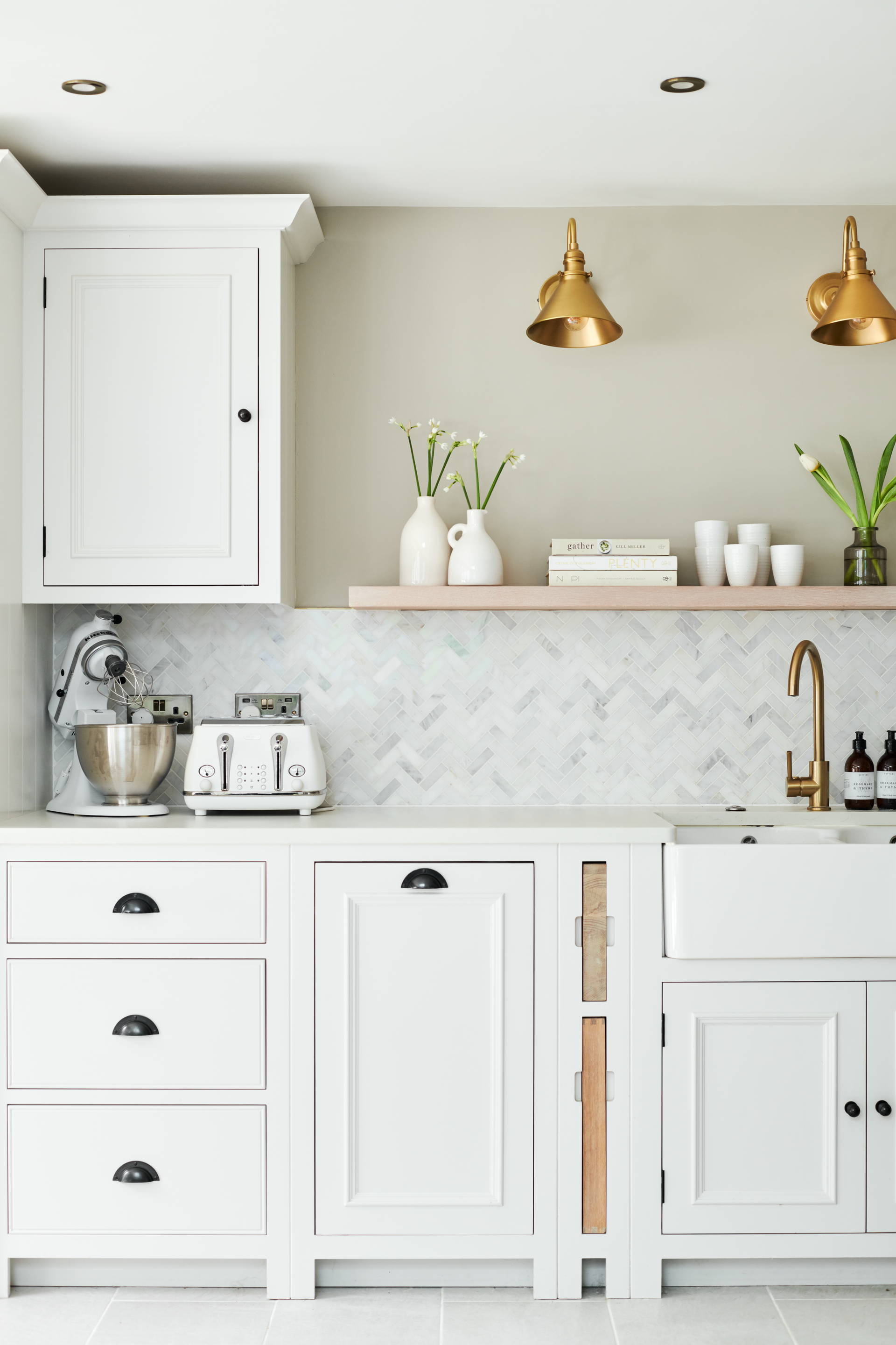 A white kitchen with inset cabinetry and a white backsplash with a herringbone configuration