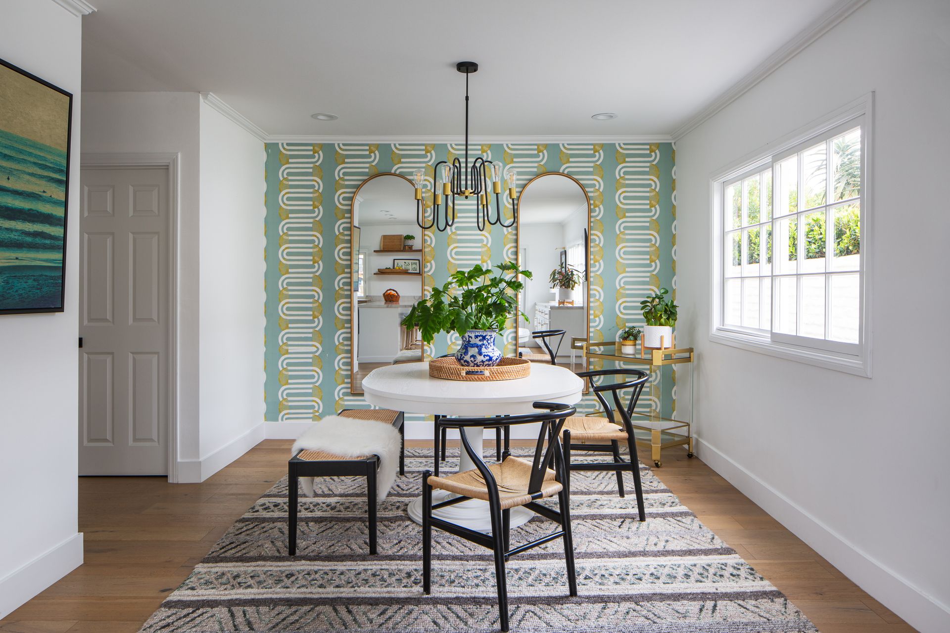 A dining room with a round table, wooden chairs, and a wallpapered accent wall