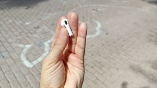 The AirPods 4 being displayed in hand