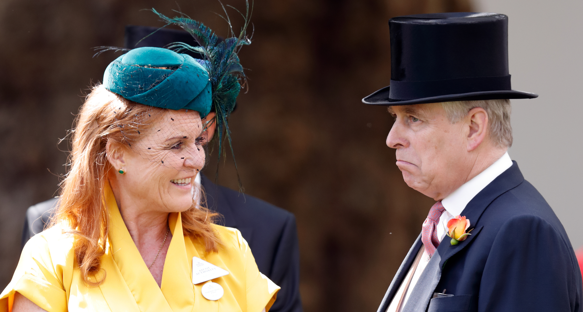 Sarah Ferguson in a yellow dress smiling at Andrew, who is scowling in a top hat
