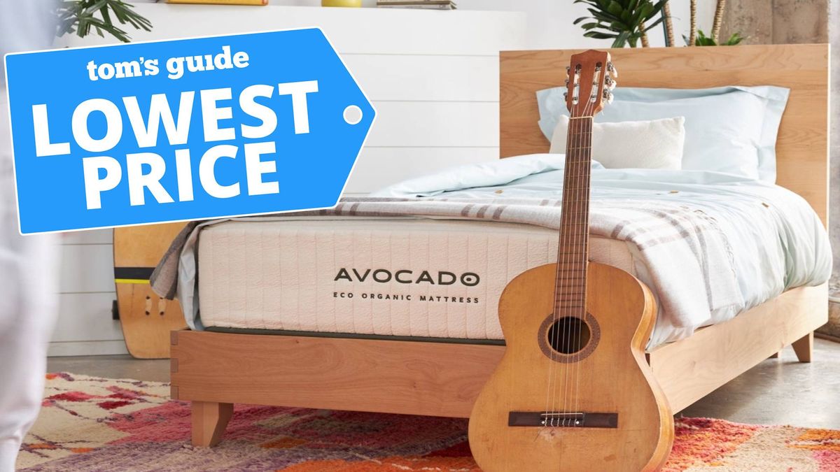 Image shows the Avocado Eco Organic Mattress on a wooden frame with an acoustic guitar leaning against the base