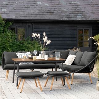 garden area with dining table and dark grey sofa with cushions