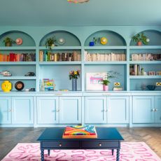 Blue living room with floor-to-ceiling built in bookcases with closed cupboards and open shelves