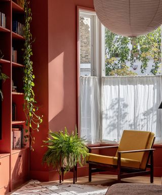 living room with muted red walls, white blinds, mustard yellow armchair