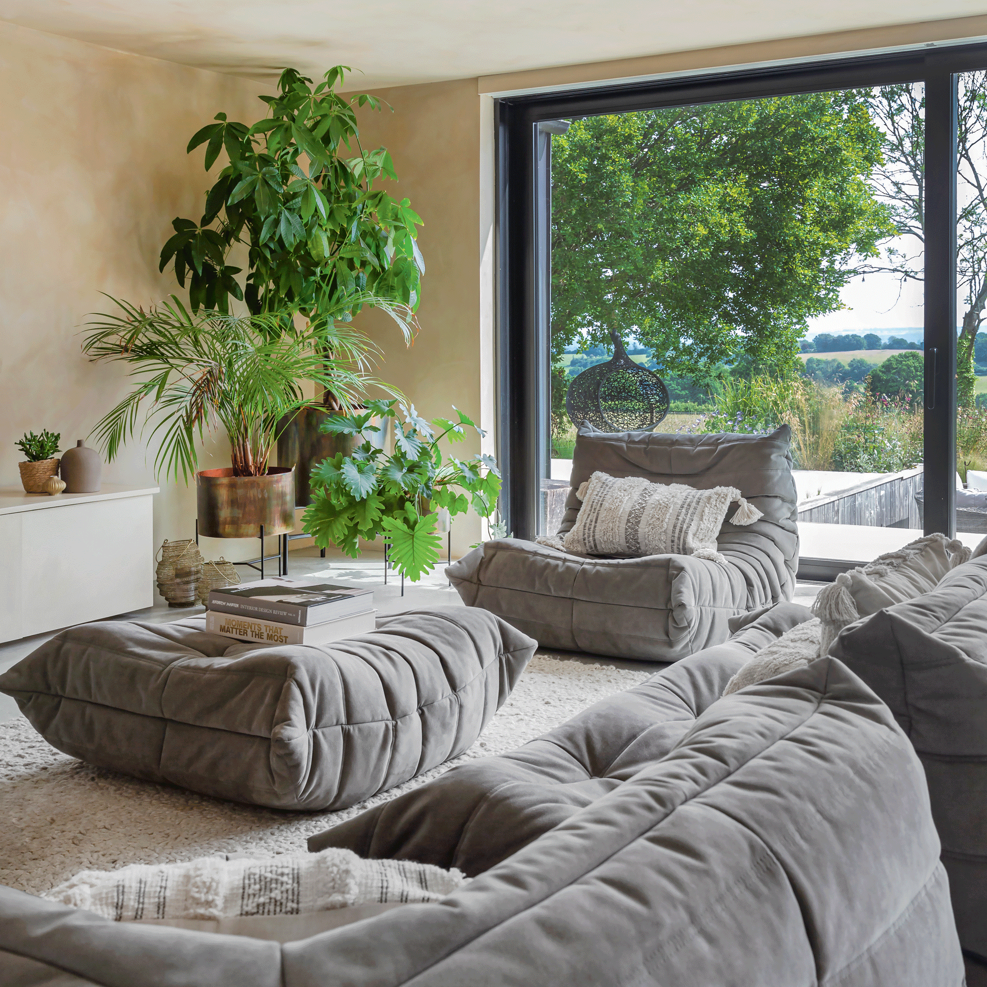 open plan living dining area with a Ligne Roset sofa set in Grey and lots of houseplants