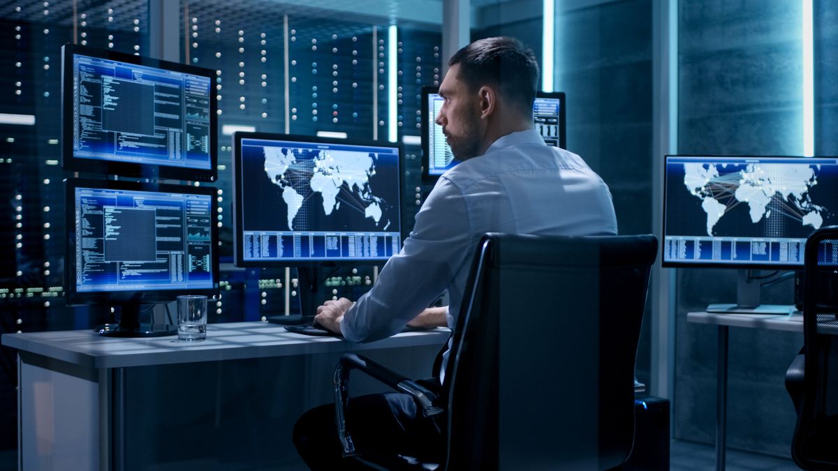 A man working with 5 monitors all displaying maps