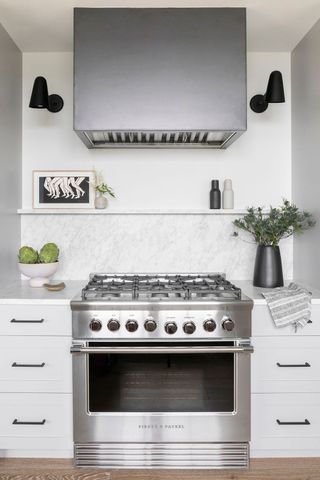 range cooker with white cabinets either side and black wall lights and extractor above