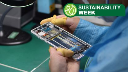 A production line worker handling a partially-built smartphone in their hand