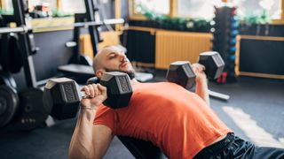 Man performing incline bench press with dumbbells