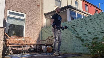 Fit&Well fitness writer Harry Bullmore performing a biceps curl in garden