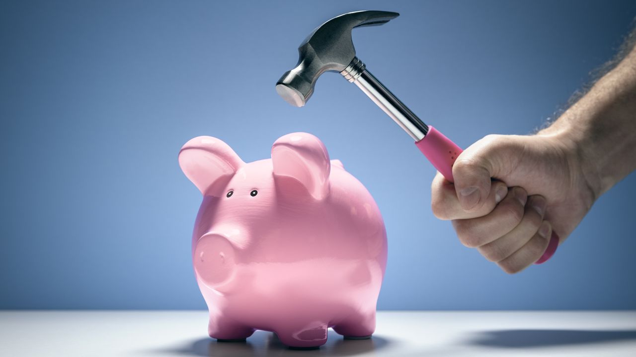 A hammer hovers above an intact piggy bank.