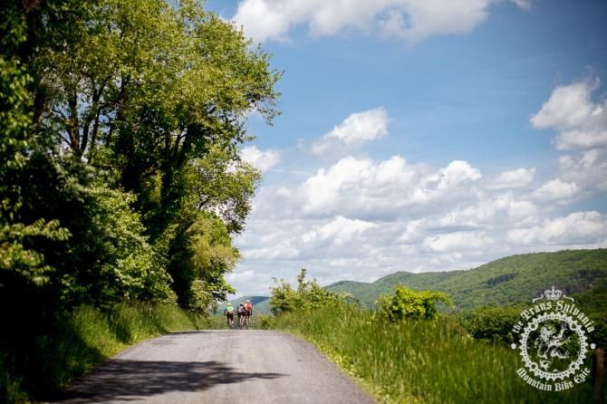 A group of riders pedal out the gravel road to wards the end of Stage 6