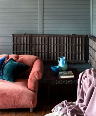 corner of room with gray-blue panelled walls, coral sofa