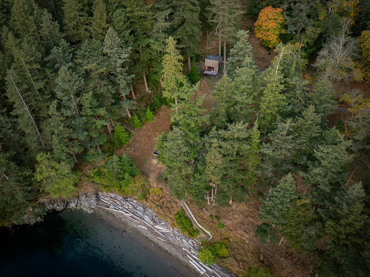 Blakely Island Cabin, a boxy structure raised on stilts above tree canopy in washington state forest
