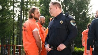 Bode Donovan wearing an orange prison jumpsuit looking at police officer Cory Walters.