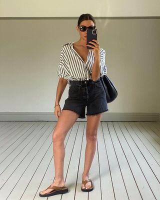 @smythsisters wearing black denim shorts with a button-up shirt and sandals