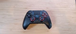 A black QRD Spark N5 PS4/5/PC controller sitting on a light wooden desk