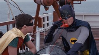Batman and Robin use the Batmobile phone on the beach