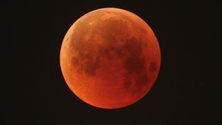 A blood-red full moon against black sky.