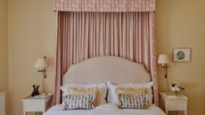 Spring bedroom with yellow pastel walls, bed canopy, printed headboard, wall sconces and yellow frilly cushions