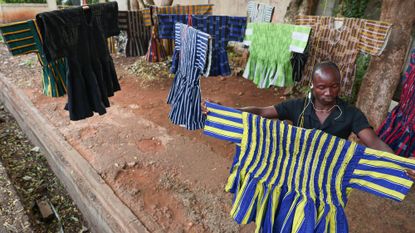 A street vendor arranges traditional garments, known as a 'fugu', as they are displayed for sale on a street in Accra 
