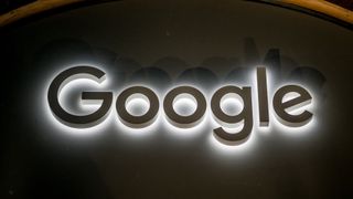 The Google logo lit in white against a dark wall. Above it, a curving piece of wall frames the logo.