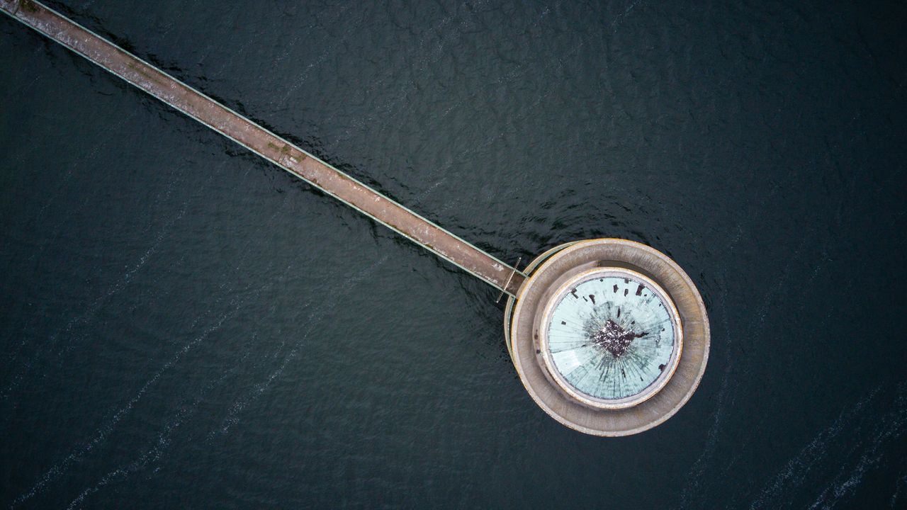 aerial view above water, with a walkway stretched across to a round landing near the bottom.