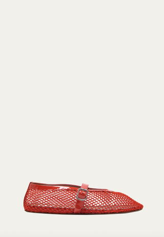 a pair of red fishnet flats by Alaïa in front of a plain backdrop