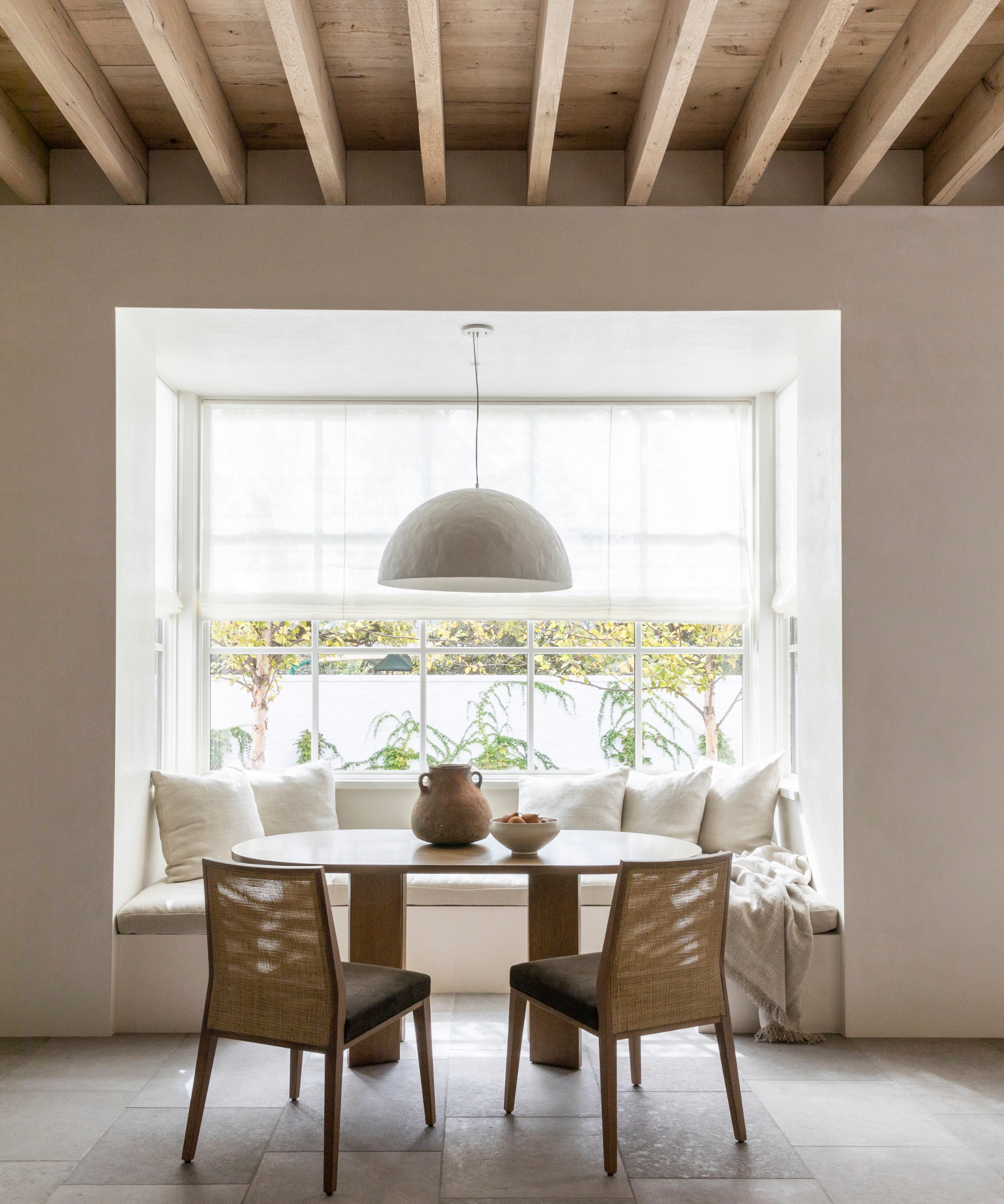 An open plan room with a cozy dining nook in the bay window