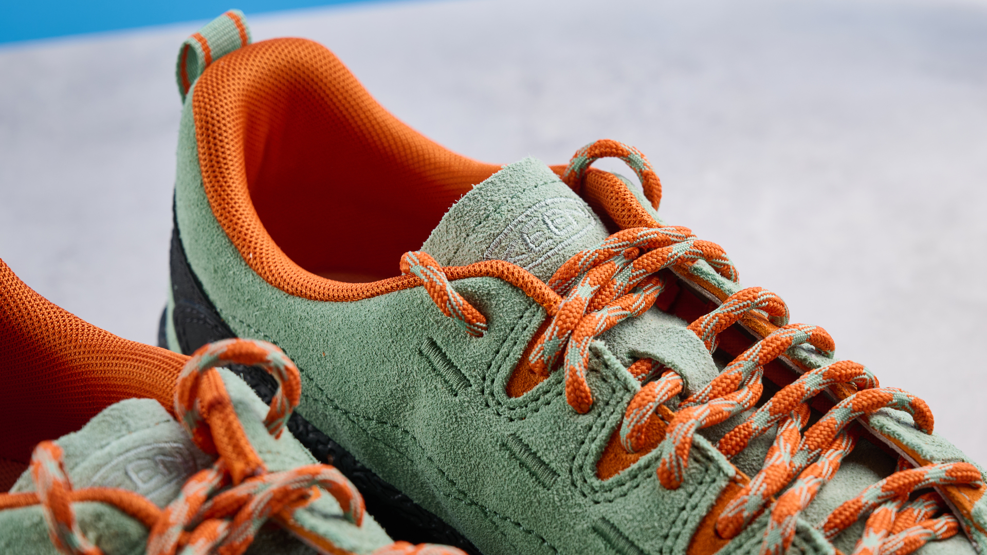 the keen jasper zionic hiking shoes in green/gold colorway photographed against a blue tom&#039;s guide background and a stone floor, showing the lug sole and the leather upper with orange laces