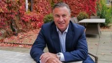 Westcon-Comstor chief executive officer (CEO) David Grant pictured sitting at a table outside wearing a navy blue suit with light blue shirt.