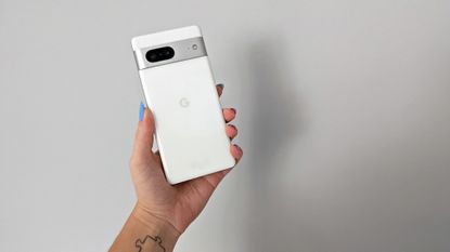 Google Pixel 7 review: holding white phone up against a wall with blue nails