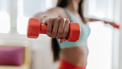 Woman trains her upper body with light dumbbells