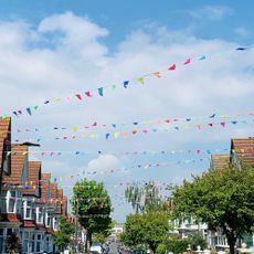 a residential street with rainbow bunting tied from one side of the road to the other, all the way down the street