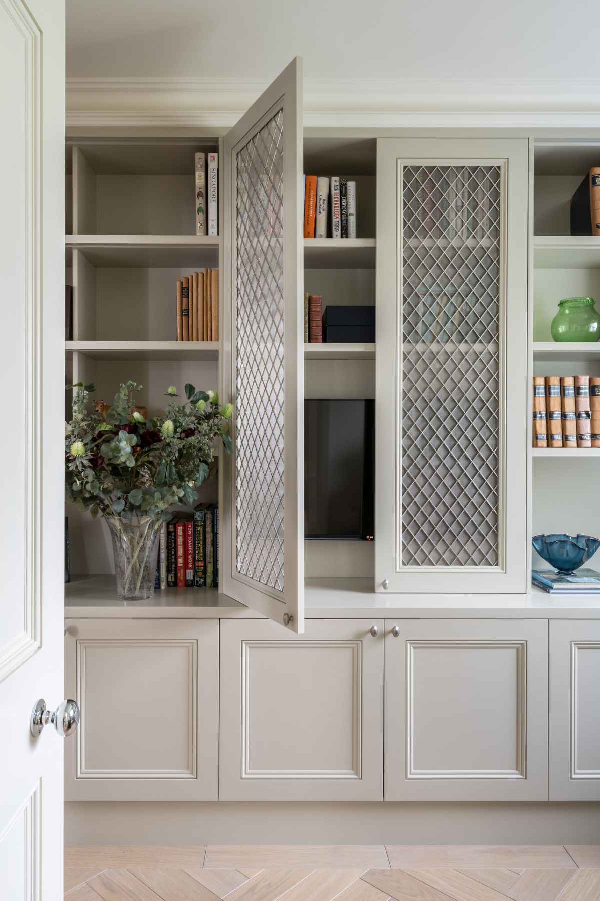 A cabinet and bookcase containing books and a vase of flowers