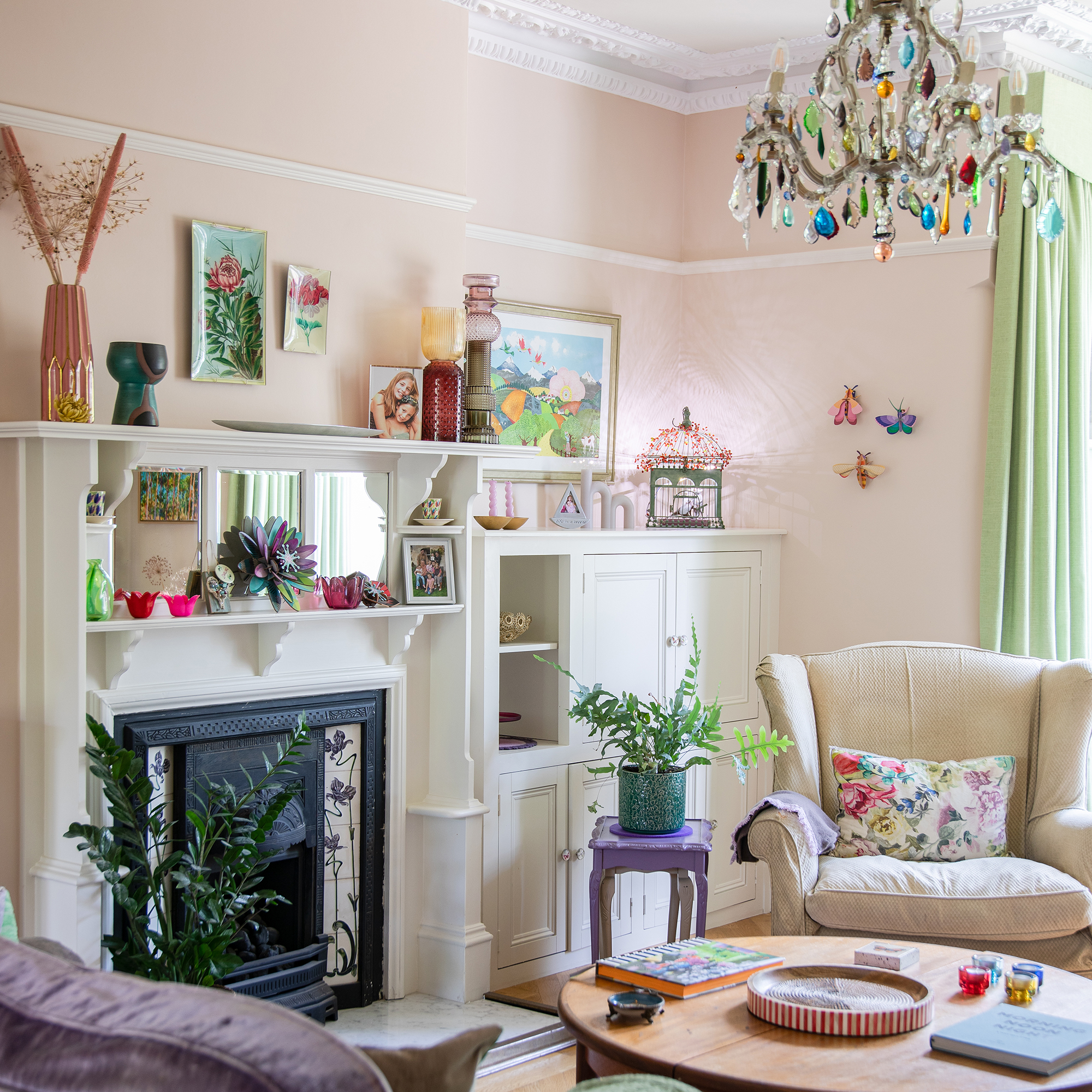 living room with colourful glass chandelier, wingback chair and pale pink walls